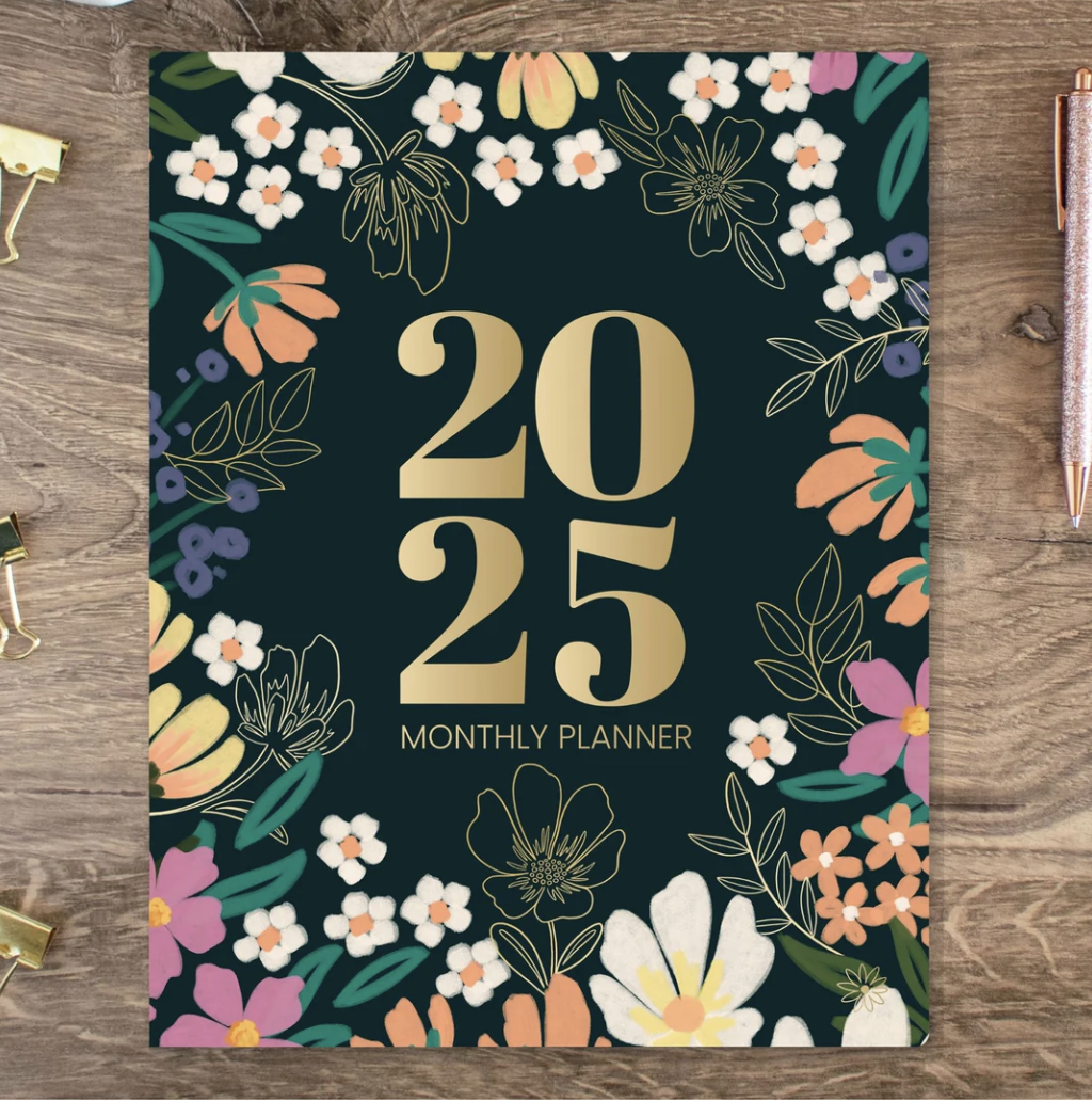 White woman in green tank top holding the Bloom 2023 daily planner in abstract green cover design